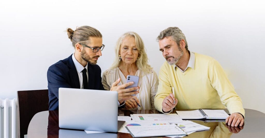 Three individuals collaborating on financial documents during a business meeting.