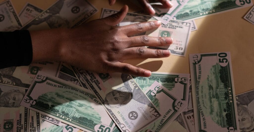 A close-up shot of hands spreading various US dollar bills on a table, highlighting financial abundance.